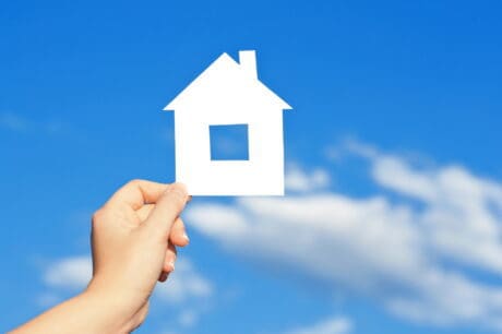 cardboard house in the hand against the blue sky